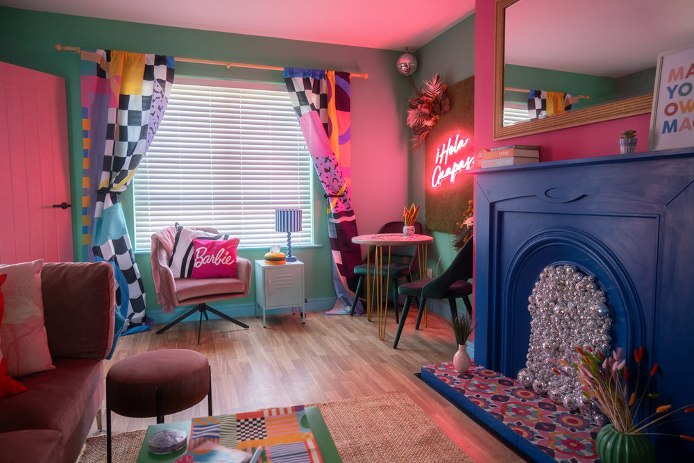 Colourful living room at Spangles Beach with pink furnishings and blue fireplace